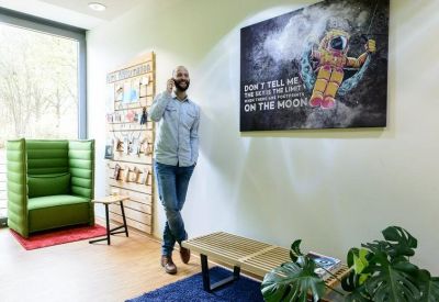 Lounge area with a tall green privacy chair and astronaut wall art.