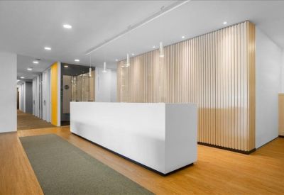 Bright reception area featuring a white minimalist desk and light wood-slat wall panels.