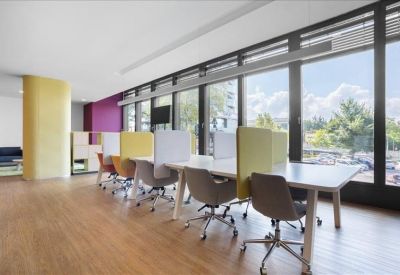Coworking space with rows of desks, ergonomic chairs, and panoramic city views.