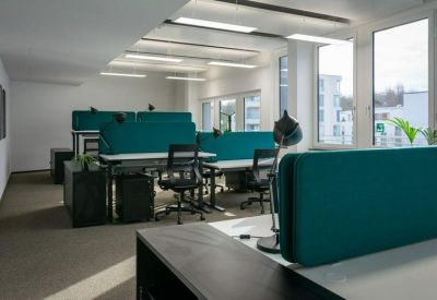 Bright open-plan office with teal privacy screens and rows of workstations.