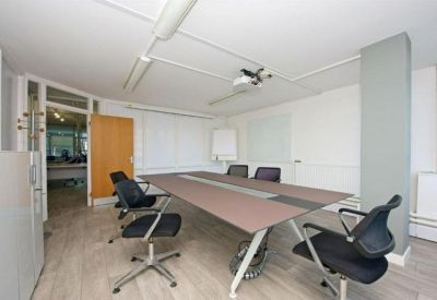 Modern meeting room with a large table, black mesh chairs, and a ceiling-mounted projector.