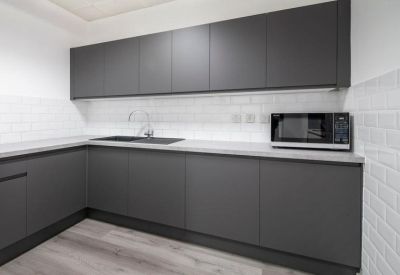 Modern communal kitchen with dark grey cabinetry and white subway tile backsplash.
