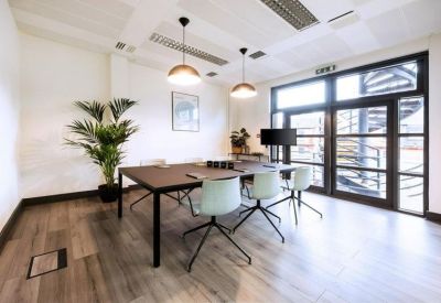 Sleek meeting room with a dark wood table, mint green chairs, and designer pendant lighting.