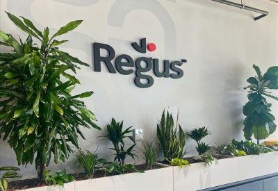 Branded reception wall with the Regus logo and indoor plants.