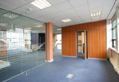 Empty office space with blue carpeting and glass partition walls.