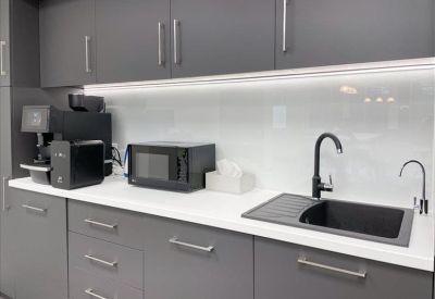 Modern office kitchenette featuring dark grey cabinetry, a black sink, and built-in appliances.