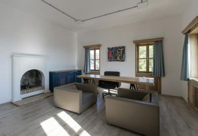 Private office featuring a white fireplace, wooden desk, and two grey armchairs.