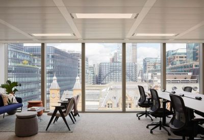 Open-plan office with white desks and floor-to-ceiling windows overlooking the city.