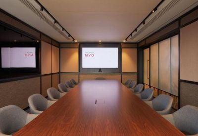 Executive boardroom featuring a long wooden table and sleek grey chairs.
