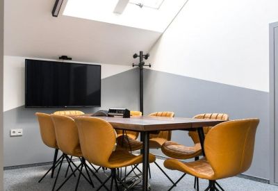 Meeting room under a bright skylight with a wooden table and yellow upholstered chairs.