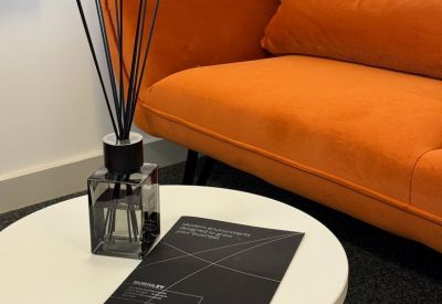Comfortable lounge area with an orange velvet sofa and a white coffee table with a reed diffuser.