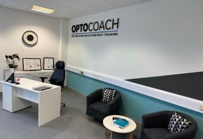 Private office suite with a white desk, blue feature wall, and two comfortable armchairs.