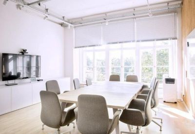 Professional meeting room with a large white table, grey chairs, and a wall-mounted television.