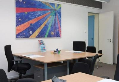 Four-person meeting table in a bright room with vibrant ray-patterned wall art.