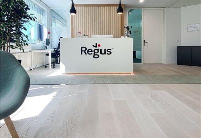 Bright reception area featuring a white desk with branding, light wood floors, and minimalist decor.