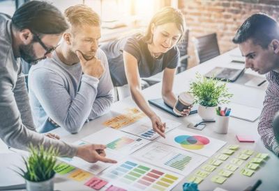 Team meeting around a table reviewing colourful charts and analytics documents.