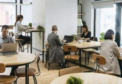 Bright coworking space with individual round tables and wooden flooring.