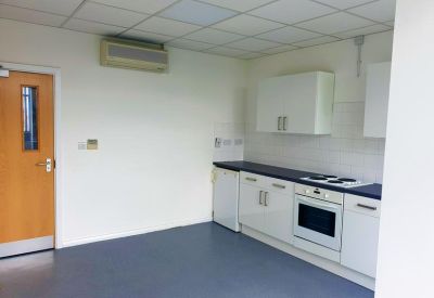 Communal kitchen area with white cabinetry and integrated oven.
