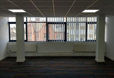 Bright office space with vertical blinds and large windows overlooking the street.