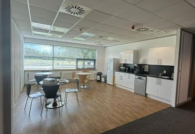 Spacious communal kitchen and dining area with wood-effect flooring and white cabinetry.