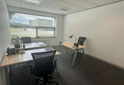 Internal two-person office suite with light-wood desks and ergonomic black chairs.