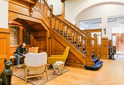 Wood-paneled lounge area with a grand staircase and comfortable seating.