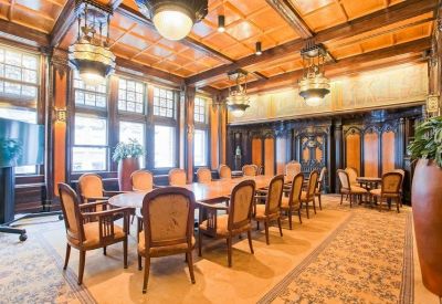 Grand boardroom with ornate wood paneling and vintage chandeliers.