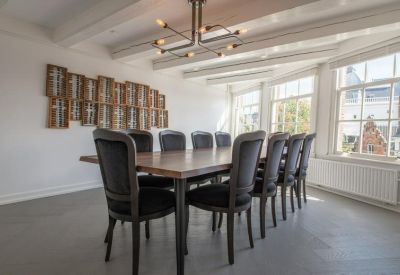 Formal boardroom with a long wooden table, black upholstered chairs, and a modern chandelier.