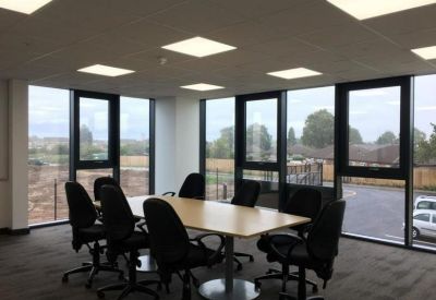 Bright conference room with a wooden table, black chairs, and large windows with natural light.