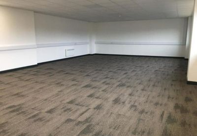 Large empty workspace with white walls and grey patterned carpeting.