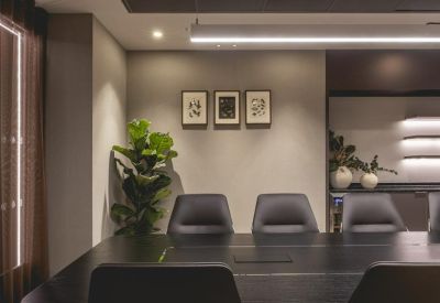 Professional boardroom featuring a large dark wood table, leather chairs, and framed artwork.