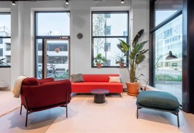 Contemporary lounge area with red armchairs, a matching sofa, and potted plants.