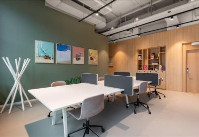 Open coworking space with white desks, grey dividers, and a sage green feature wall.