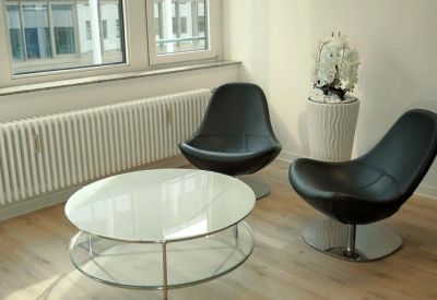 Casual waiting area featuring two black swivel chairs and a round glass coffee table.