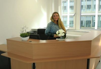 Professional reception area with a wooden desk, white flowers, and a friendly receptionist.