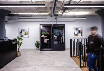 Clean white hallway featuring private phone booths and abstract framed art.