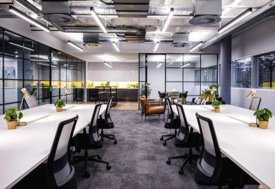 Bright open-plan office with white communal desks and ergonomic chairs.