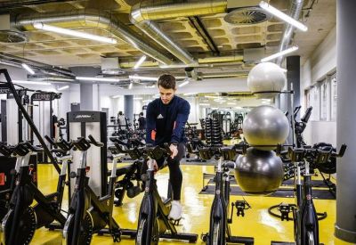 Fitness center with stationary bikes and exercise balls on a bright yellow floor.