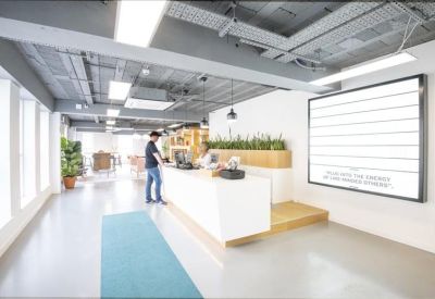 Minimalist white reception desk with integrated greenery and wall-mounted display.