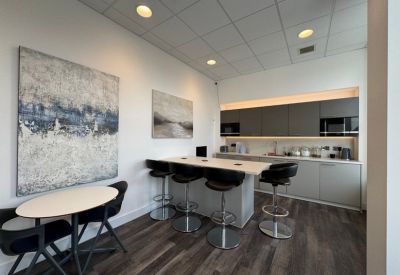 Breakout area with a small round table, high bar stools, and abstract wall art.