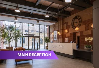 Spacious main reception with a sleek desk, industrial ceiling, and vintage clock wall.