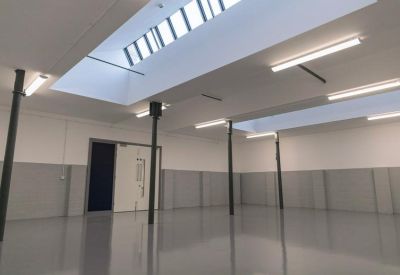 Spacious, empty industrial-style room with high ceilings and skylights.