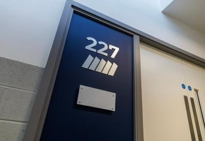 Close-up of a navy blue door with silver room numbering and signage.