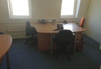 Private office suite with two wooden desks and natural light from large windows.