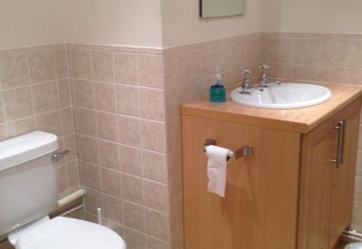 Simple bathroom featuring a white toilet, wooden vanity, and neutral tiling.