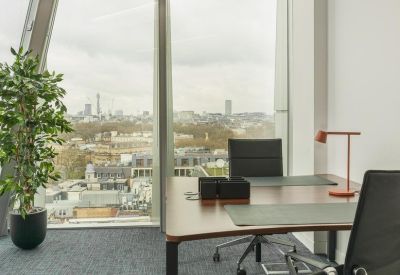 Modern private office with a wooden desk, floor-to-ceiling windows and city views.