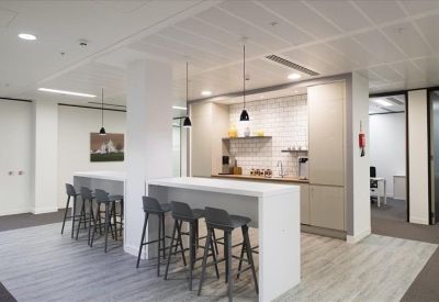 Bright modern kitchen and breakout area with white breakfast bars and stylish pendant lighting.