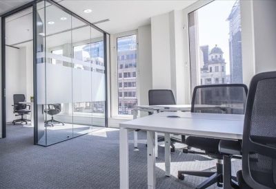 Open-plan office space featuring white desks and a frosted glass-walled meeting room.