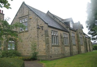 Side angle of a stone building with multiple tall windows and a slate roof.