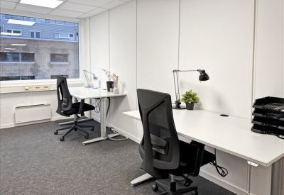Private office space featuring two white desks with black ergonomic chairs and a window view.